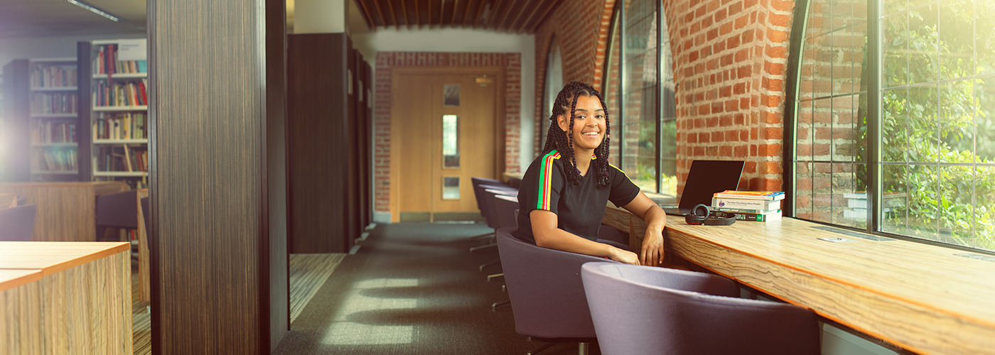 A female student sat in the Hope library smiling at the camera